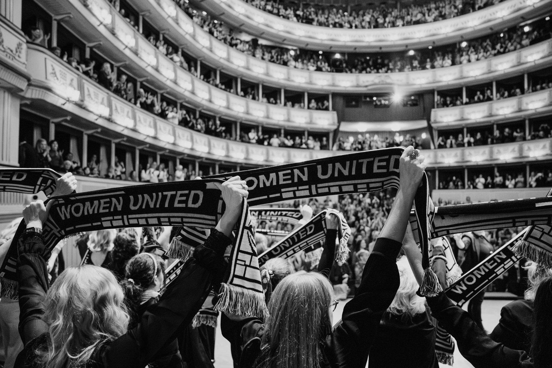 Frauen in der Wiener Staatsoper halten Schals mit der Aufschrift „Women United“ hoch